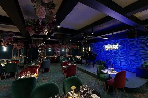 scène, tables, chaises, fleurs au plafonds, miroirs, ambiance tamisée