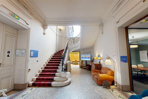 Esaclier menant a un espace de coworking et salle sous l'escalier avec accès à la cuisine et un autre espace de coworking